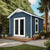 Modern backyard shed with French doors, a small porch, and potted plants around it.