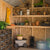 Organized wooden shelves, labeled storage crates, gardening tools, potted plants, and a metal roof.