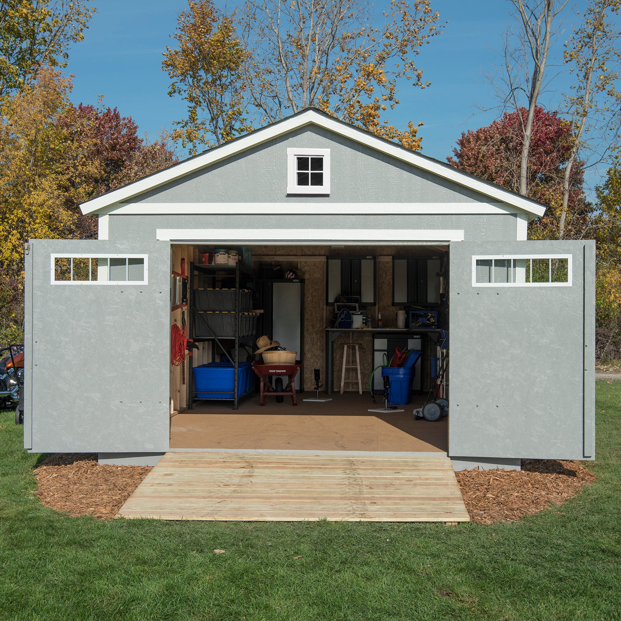 Storage shed with double doors opened to reveal organized shelves, with tools and gardening supplies inside.