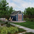 Backyard storage shed with decorative double doors, transom windows, and a fire pit seating area nearby. 